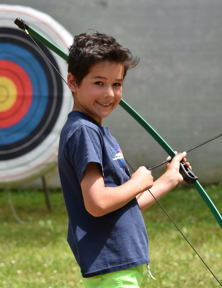 Boy smiling holding bow & arrow.