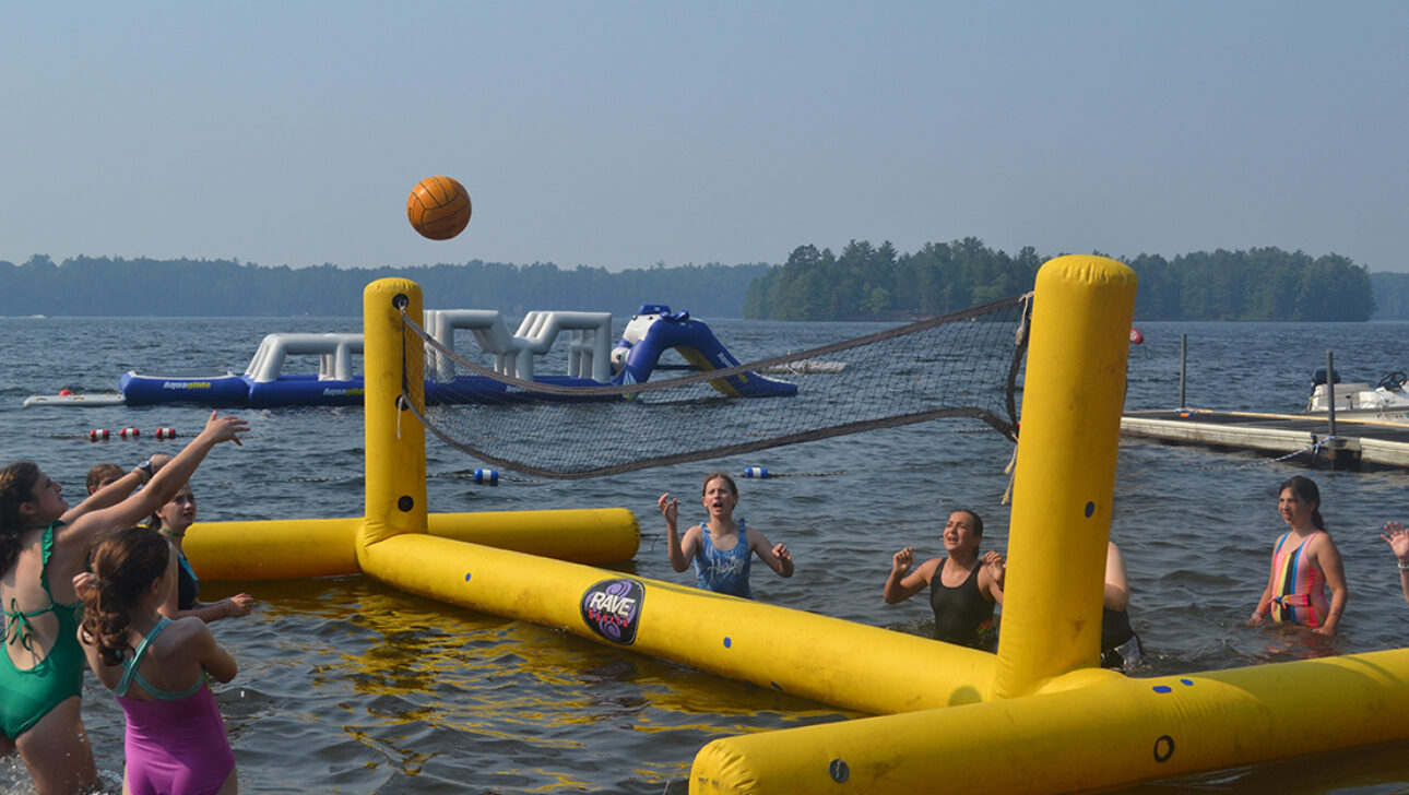 Campers playing volleyball in the water.