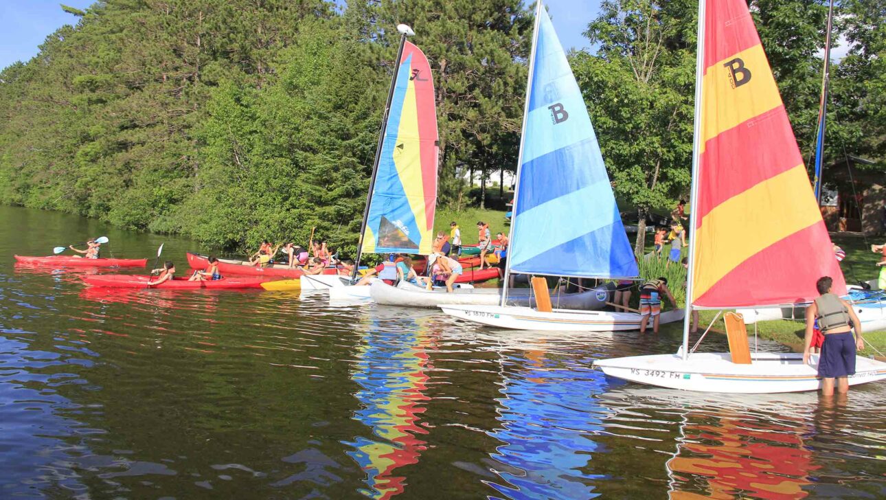 Sailboats and kayaks on a lake.