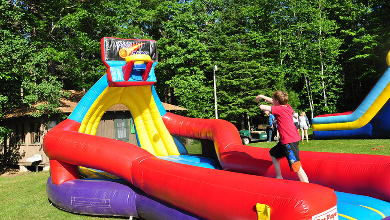 A camper throwing a basketball on an inflatable basketball hoop.
