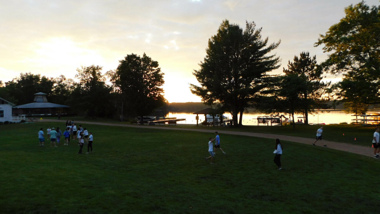 Campers playing on the lawn at sunset.