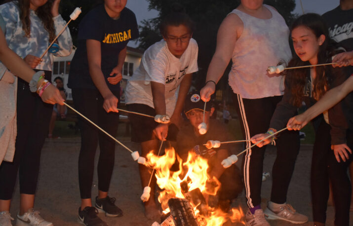 Shoafim campers roasting marshmallows over a fire.