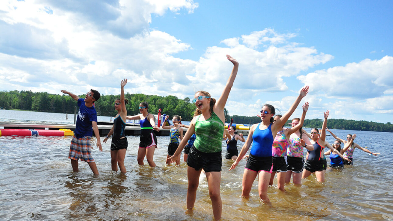 A group of campers doing stretches at a lake.