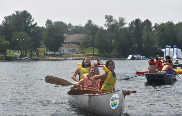 Three Machon campers riding a canoe.