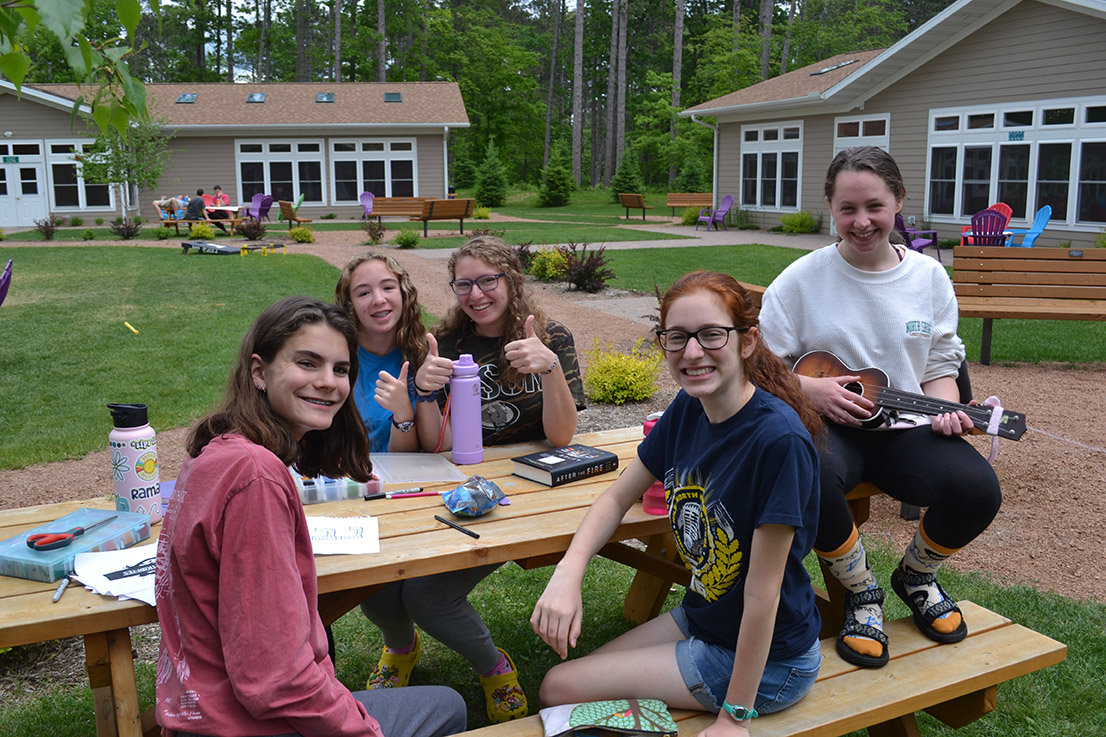 A group of campers sitting at a table outside.